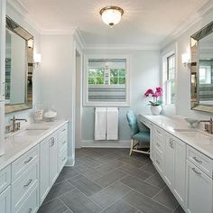 a large bathroom with two sinks and mirrors on the wall, along with white cabinets