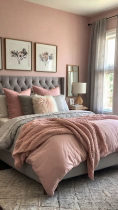 a bedroom with pink walls and gray bedding in the center, two framed pictures on the wall