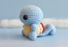 a small crocheted turtle sitting on top of a blue surface with a black eye