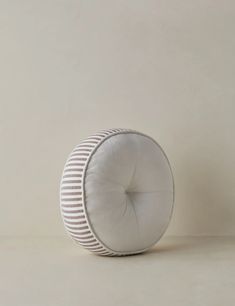 a round cushion sitting on top of a white floor next to a brown and white wall