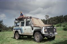 a man sitting on top of an old jeep