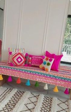 a pink bench with colorful pillows and pom - poms on it