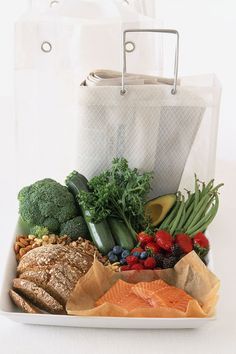 there are many different types of food in the box on this plate, including fish, broccoli, strawberries, cucumbers, and other vegetables