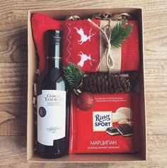 a bottle of wine, chocolate and christmas decorations in a box on a wooden table