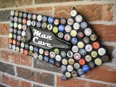 a bottle cap map on the side of a brick wall that says man cave with beer caps all over it