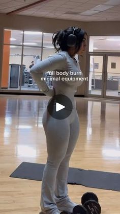 a woman standing on top of a skateboard in a gym with her back to the camera