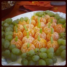 there are many oranges and grapes on the plate with green stems in between them