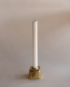 a white candle sitting on top of a gold holder