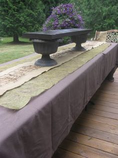 a long table with two benches on it in the middle of a yard, covered by a blanket