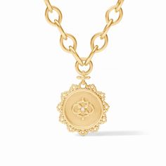 A mother of pearl disc encircled by delicate golden floral filigree dangles from a chain of smooth navette links.