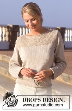 a woman is standing on the beach with her hands in her pockets