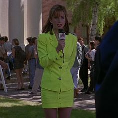 a woman in a lime green suit is talking on the phone and holding a microphone