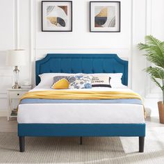 a bed with blue upholstered headboard and foot board in a white room