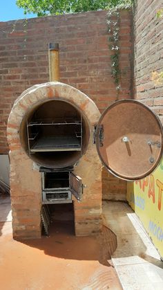 an outdoor pizza oven is shown in front of a brick wall