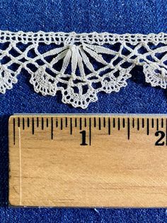 the measuring tape is next to a piece of crocheted lace on blue fabric