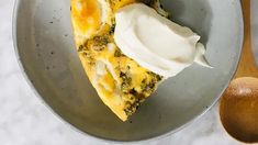 a slice of broccoli and cheese quiche on a plate with sour cream