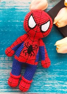 a crocheted spiderman doll sitting next to tulips on a table