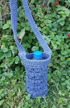 a blue crocheted water bottle holder in the grass