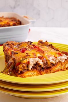 a yellow plate topped with lasagna covered in cheese and sauce next to a casserole dish