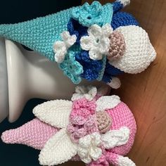 crocheted hats with flowers on them sitting on top of a mannequin head