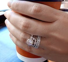 a close up of a person's hand holding a coffee cup with two rings on it