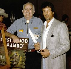 two men standing next to each other in front of a sign with a knife on it