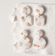 several pieces of white and orange stone with gold earring posts on a white surface