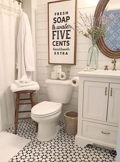 a white toilet sitting next to a sink in a bathroom under a framed sign on the wall