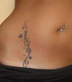 a woman's stomach with a tattoo design on the side and an ear piercing