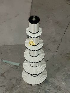 a stack of white paper plates sitting on top of a cement floor next to a wall