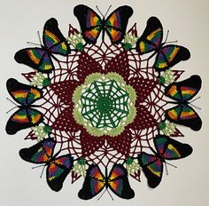 a crocheted doily with many different colored butterflies in the center and on top of it