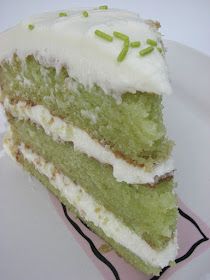 a piece of green cake with white frosting and sprinkles on top