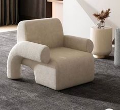 a beige chair sitting on top of a carpeted floor next to a white vase