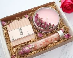 an open gift box with pink flowers and body lotion on the table next to it