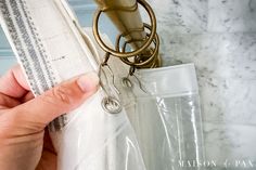 a person is opening the curtain in front of a bathroom mirror with a pair of scissors