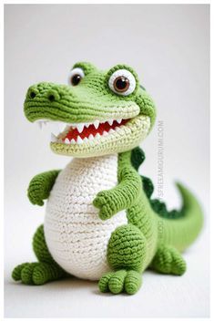 a crocheted stuffed alligator sitting on top of a white surface with it's mouth open