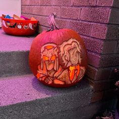 a carved pumpkin sitting on top of a step next to a brick wall and purple steps