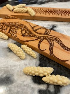 an intricately carved wooden board with white beads on it and two pieces of wood next to it