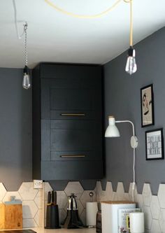 a kitchen with black cabinets and white hexagonal tiles on the wall above it