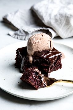 a piece of chocolate cake with ice cream on top is sitting on a white plate