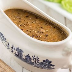 a bowl filled with soup sitting on top of a table next to lettuce