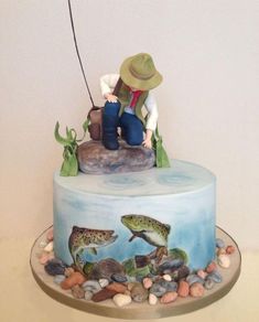 a cake with a fisherman on top of it and fish in the water around it