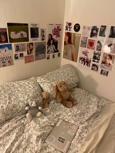 two teddy bears sitting on top of a bed in a room with pictures all over the wall