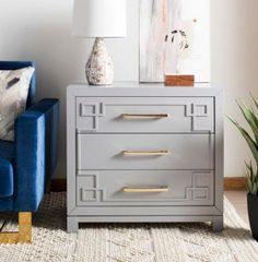 a grey chest of drawers with gold handles in a living room next to a blue couch