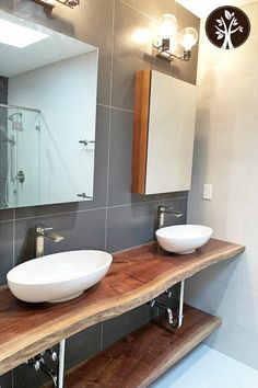 two white bowls sit on top of a wooden shelf in front of a bathroom mirror