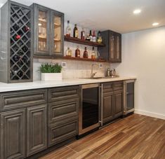 an empty kitchen with wooden floors and gray cabinetry, wine rack on the wall