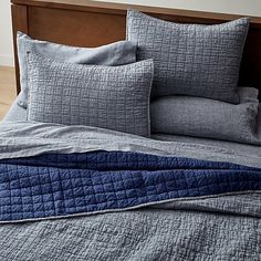 a bed with blue and grey quilts on it