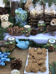 a table topped with lots of cookies and other items on top of a cloth covered table