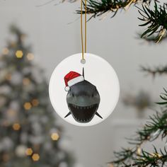 a christmas ornament with a shark wearing a santa hat hanging from a tree