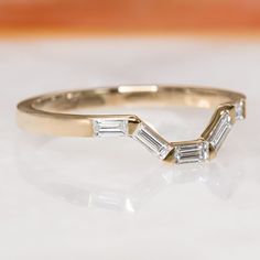 a gold ring with three baguets on the side, sitting on a white surface